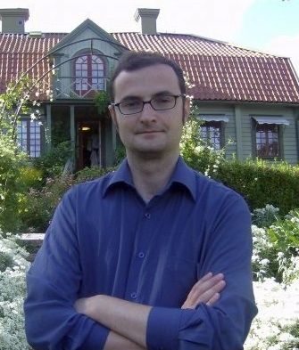 Professor Enrico Raffaelli standing in front of a house with flower garden