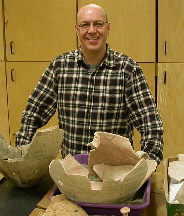 Archaeology Lab Manager Stanley Klassen standing behind a table with pottery